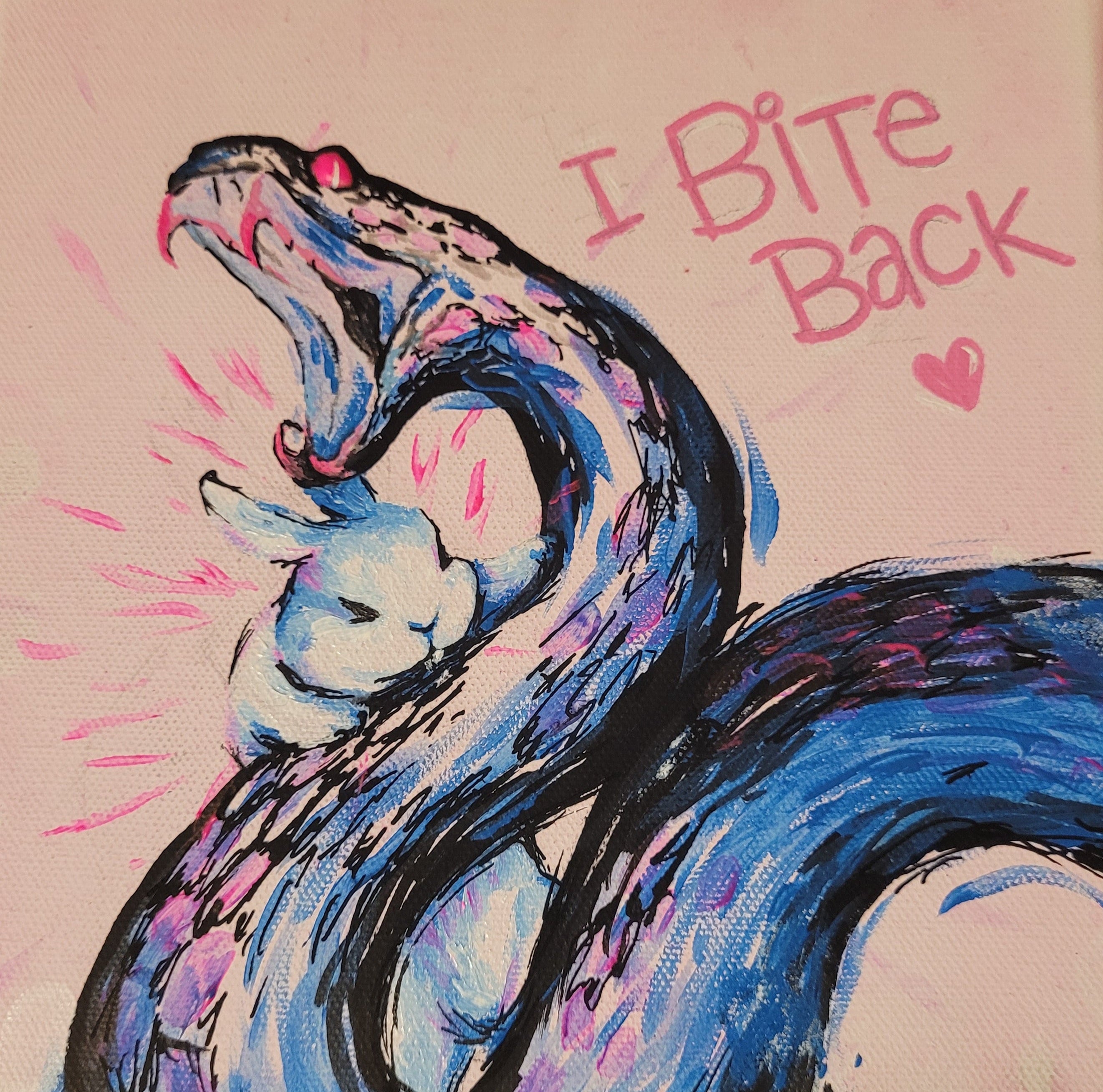 A square canvas painting featuring a blue and black snake wrapping around a white rabbit while the rabbit bites it, with pink text reading 'I Bite Back' and a small pink heart on a light pink background.